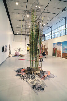 An art installation made of chain link fence, stone, paint, pick hammer, plastic, fibers, wire.