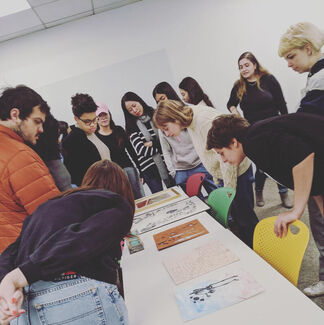 Students of varying ethnicities, ages, and genders view artwork. 