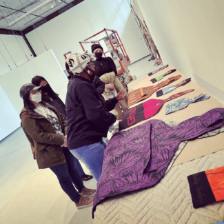 Five masked people of varying ethnicities, genders, and ages, viewing artwork. 