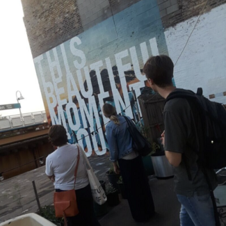 Three students viewing a mural. 