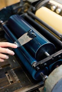 A close up shot of someone's hand as they work in the letterpress studio.