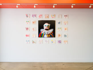 Gallery wall of clown illustrations with a larger clown photo in the middle. 