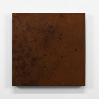 A dark brown square-shaped block with painted circle-like shapes. 