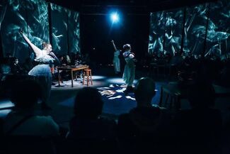 Performers and an audience in a black box theater.