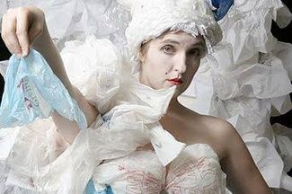 An adult person with a fair skin tone dressed in a Marie Antoinette costume made of plastic and paper. 