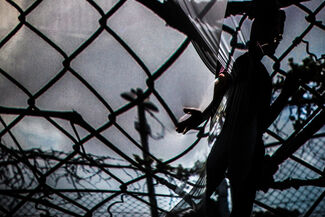 Distortion of a person's silhouette and a chain link fence. 