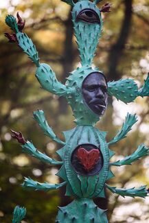 Sculpture of a cactus with a human face and different anatomical organs. 
