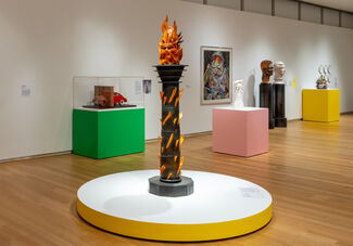 Sculpture of a lit torch containing the head of a person.