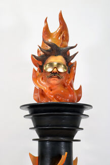 Sculpture of a lit torch containing the head of a person wearing sunglasses.