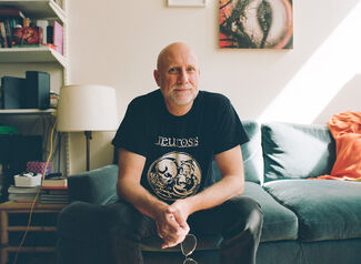 Trevor Paglen, an adult person with a fair skintone, seated on a couch. 