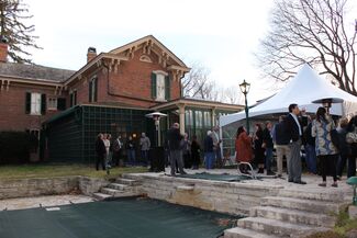 Party guests mingle outside of a brick home on a stone patio above a covered pool