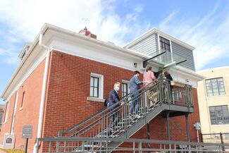 People climb exterior back stairs to enter studio