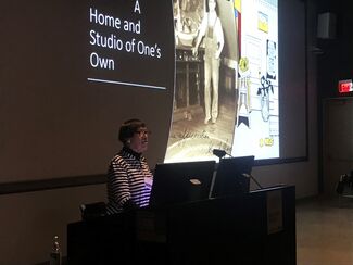 Wanda gives a presentation on A Home and Studio of One's Own next to a projector screen
