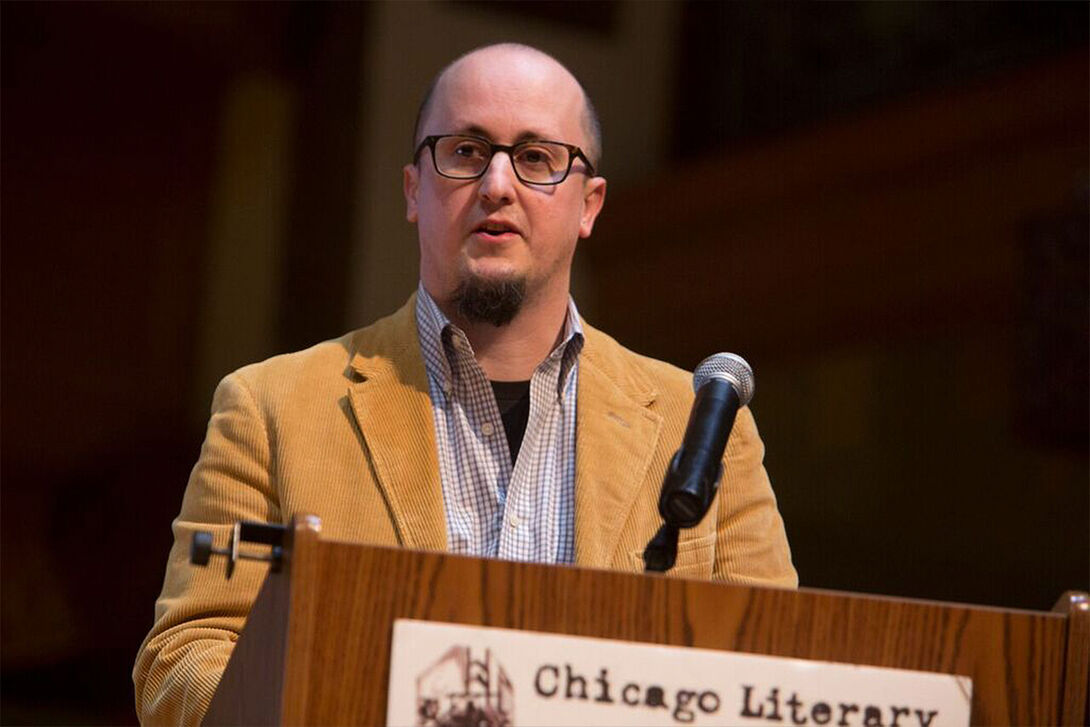 An image of Adam Mack speaking at a podium.