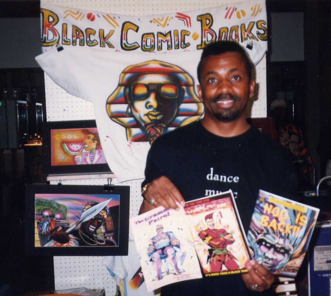 Turtel Onli holds his comics in front of a sign that reads Black Comic Books
