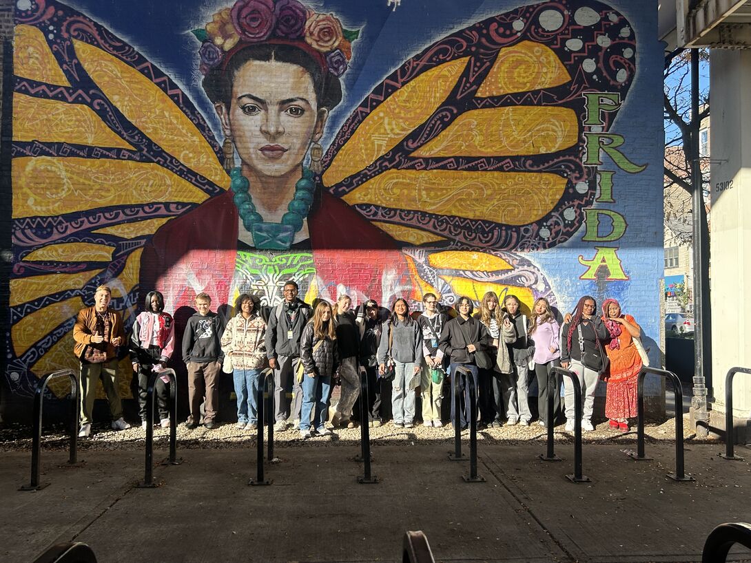 A group of CAAP students stand outside in front of a Frida Kahlo wall mural.