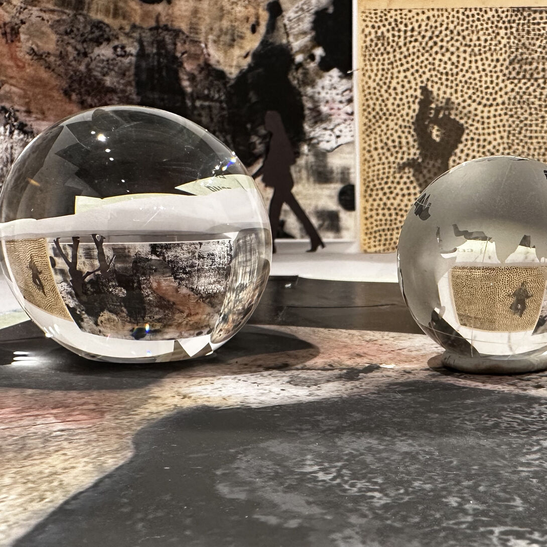 Two glass spheres of different sizes invert the silhouetted figures in the background.. 
