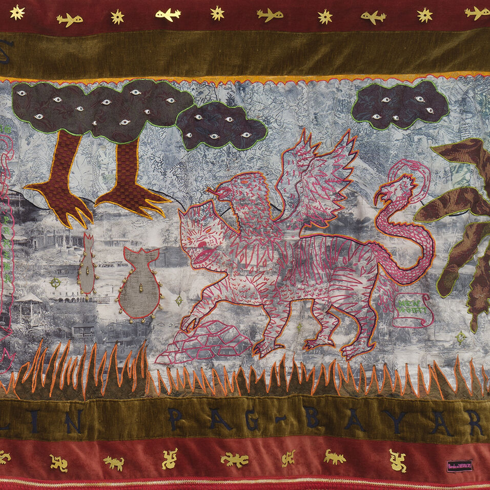 Detail of hand-embroidery on top of photo-transfer on fabric. Features a mythical creature in pink and orange outlines stitches, flames, bombs and dark clouds with eyes.  