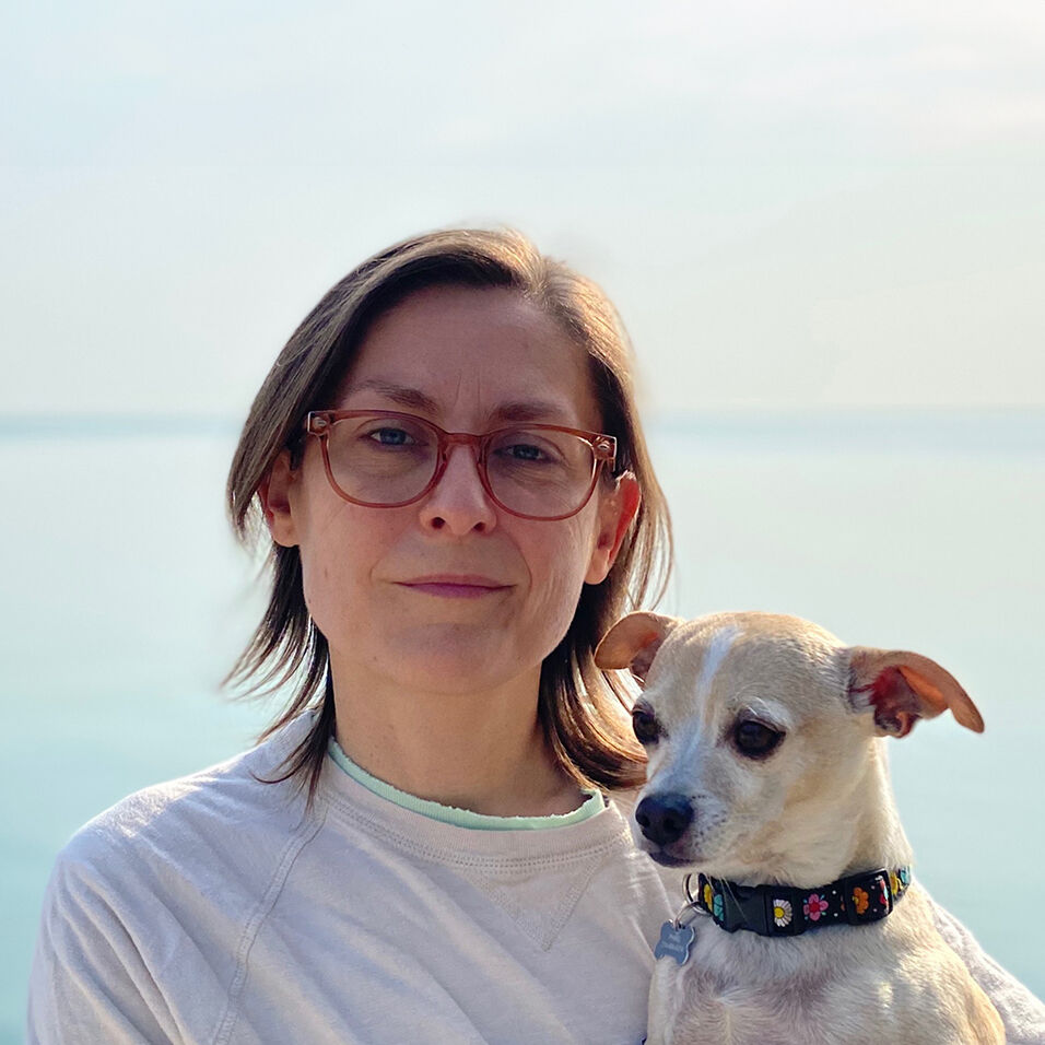 Headshot of the artist and their dog in front of a lake horizon.