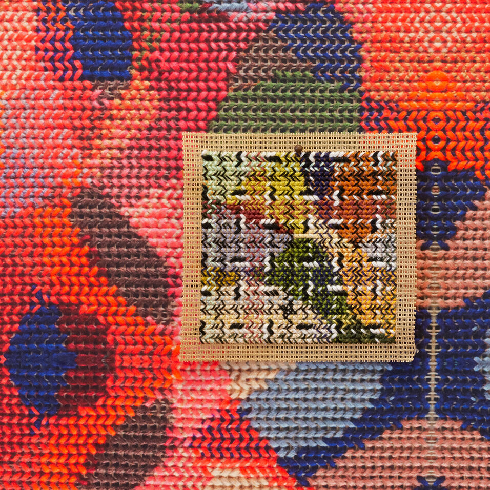 Close up detail of colorful, abstract needlepoint with a square of a different pattern inside.