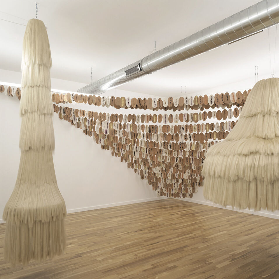 An installation shot of three hanging sculptures in neutral tones. 