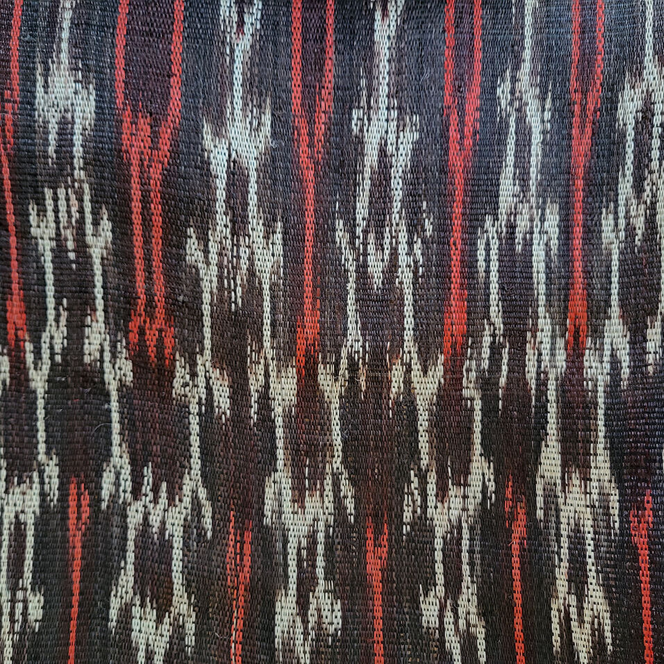 Detail of woven cloth with a black, white and red pattern.