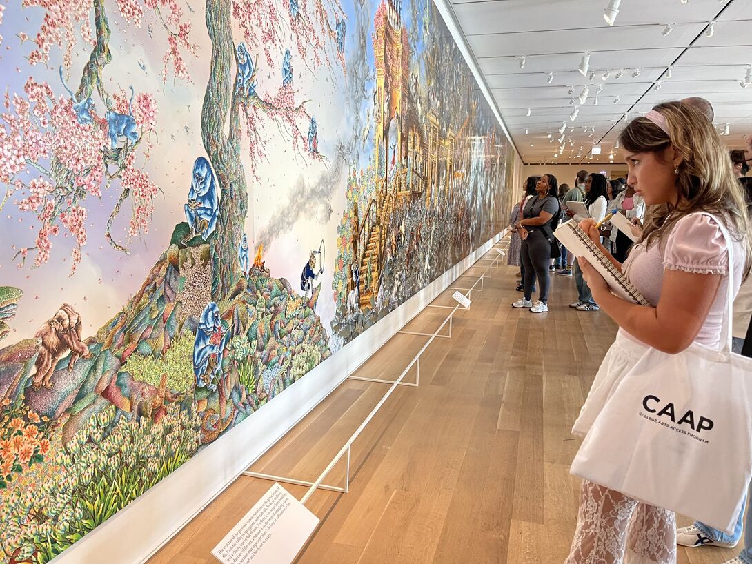 A student with a CAAP tote bag observes a mural. 