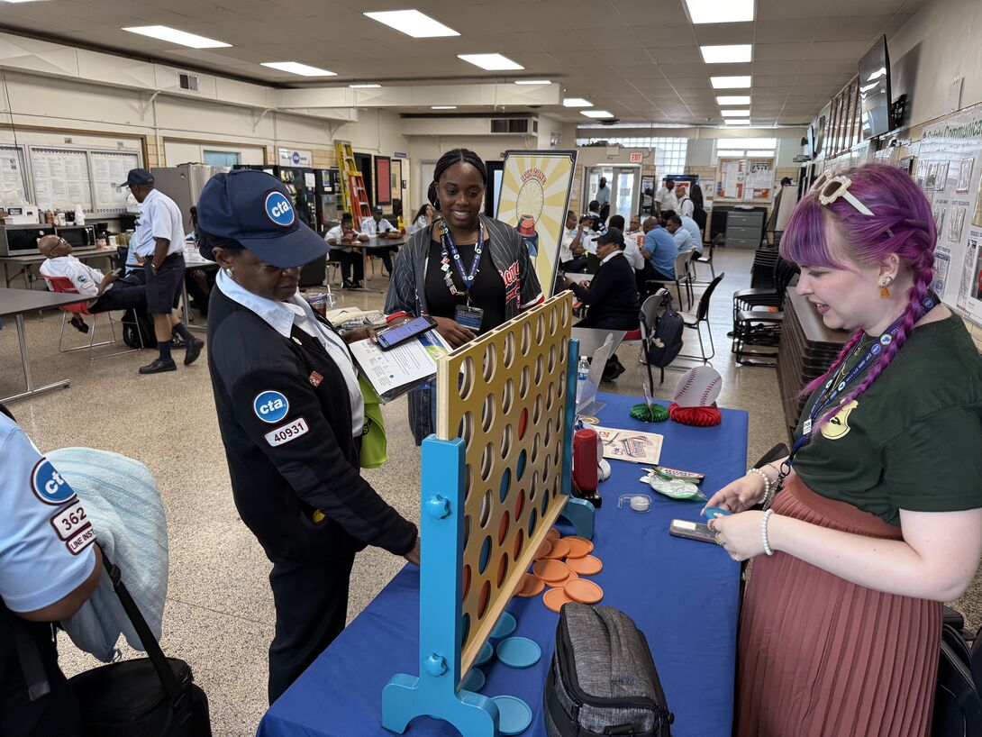 Lauren Nickels and CTA employees play a large tabletop Connect Four game during an employee engagement event.