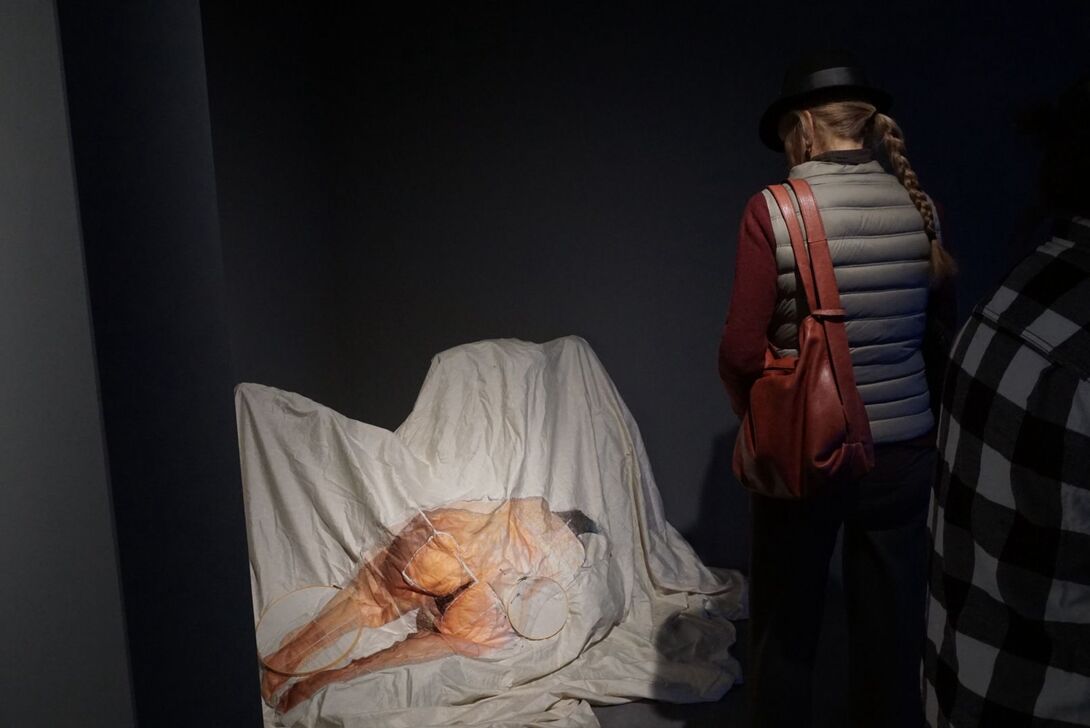 A person stands over the piece FAKER by Jen LaMastra