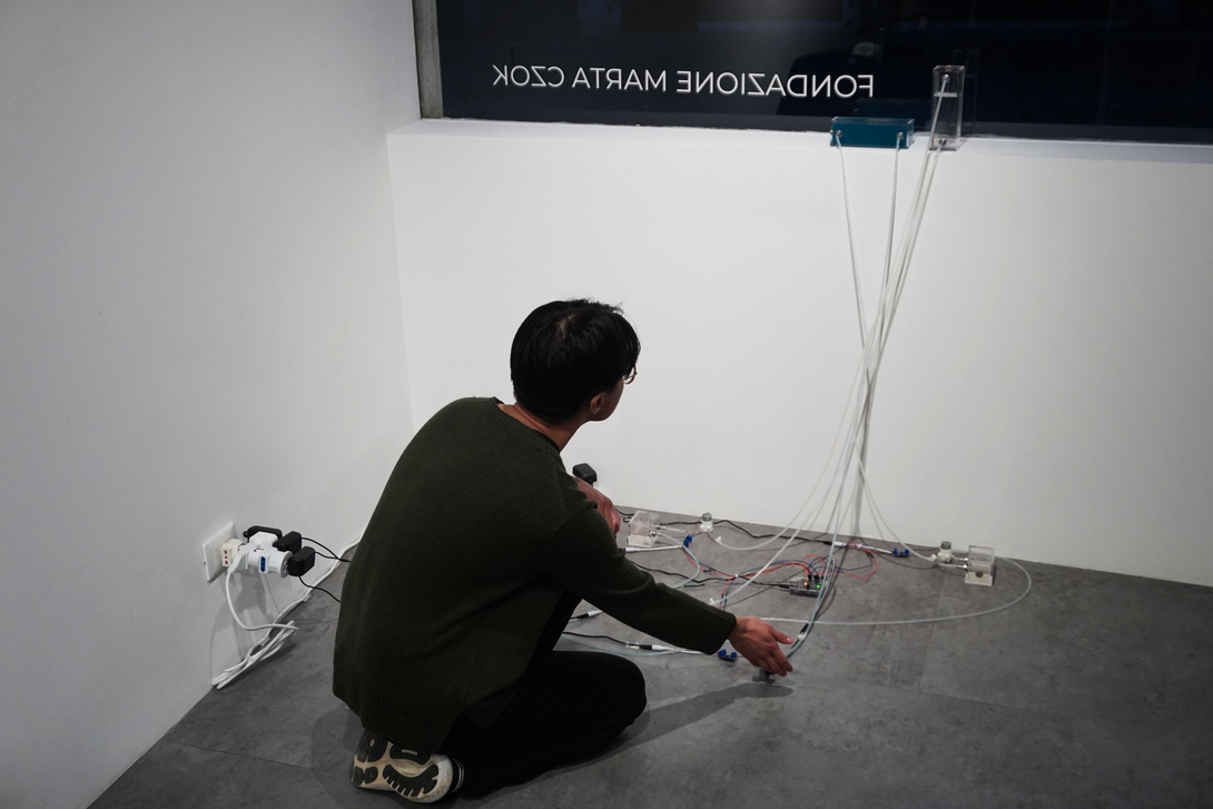 Flows Between Live audio from contact microphone, ultrasonic distance sensor, humidifier, dosing pump, multi-channel sound Beile Hu  A contact microphone on the gallery window detects the unseen currents of daily life: our footsteps, movements, and interactions with the gallery and the street. This real-time data becomes a multi-channel soundscape, revealing how our built environment listens to and transforms traces of human presence.