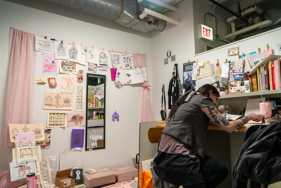 A student works on comics at a desk. 