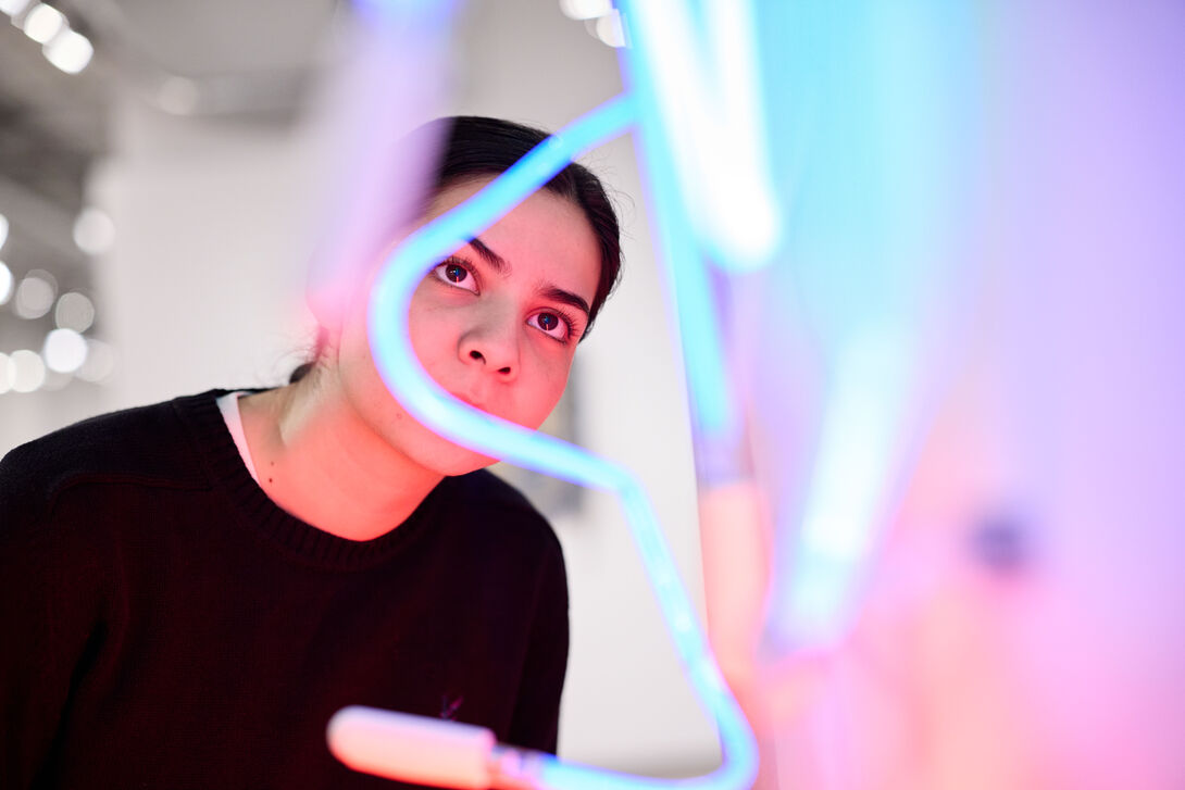 A person views a neon light artwork. 