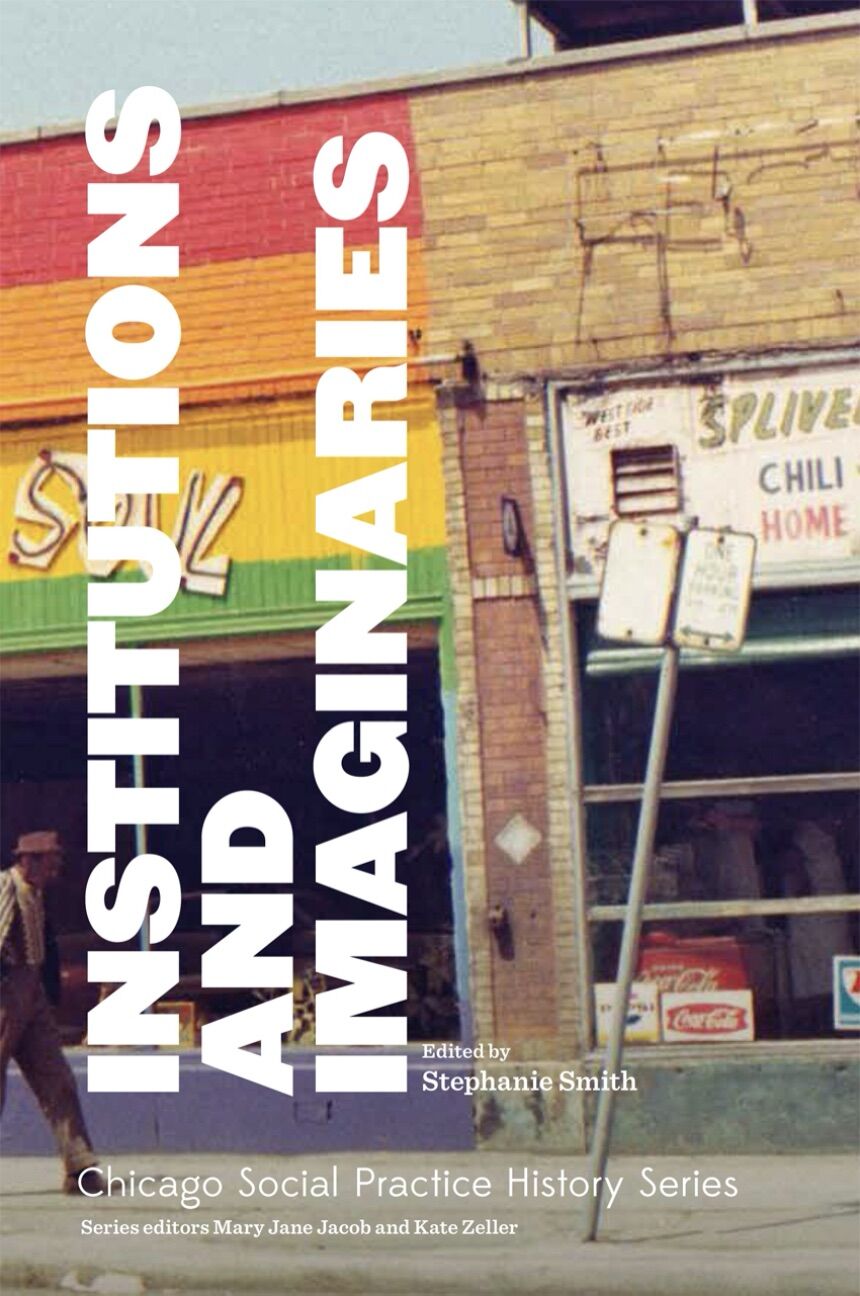 A man walks down a sidewalk in front of a row of brick storefronts, half of which are painted in horizontal rainbow colors