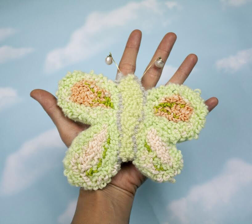 Hand holding a knit butterfly