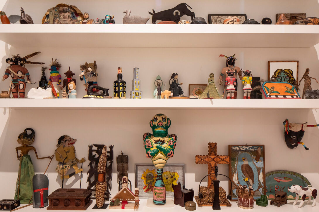 Several shelves with a collection of art objects and statues of figures, buildings, and crosses