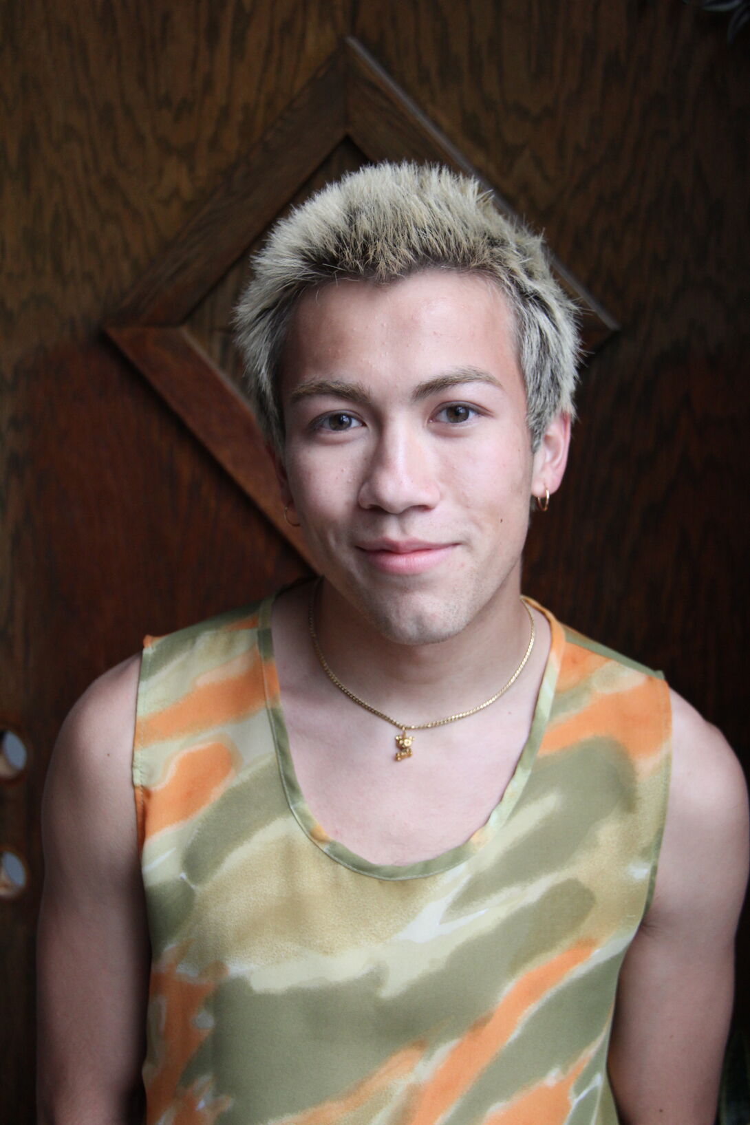 A student poses for a profile photo in front of a wooden wall